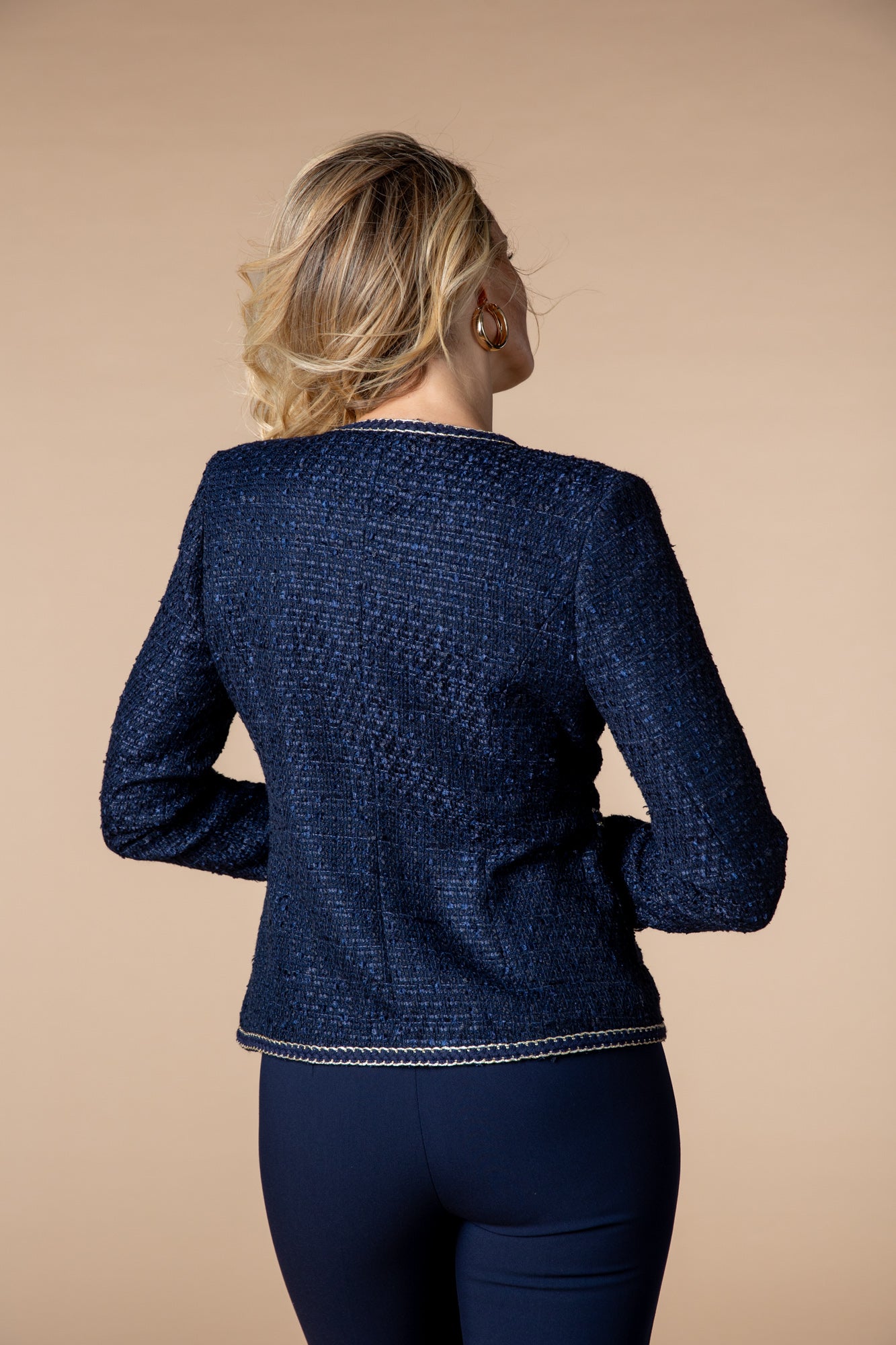 Dunkelblaue Jacke mit eleganter Bordüre in Dunkelblau und Gold. Ideal für sowohl geschäftliche Anlässe als auch lässige Alltaglooks, kombiniert sie Stil mit praktischen Details wie Taschen und Häkchenverschluss.