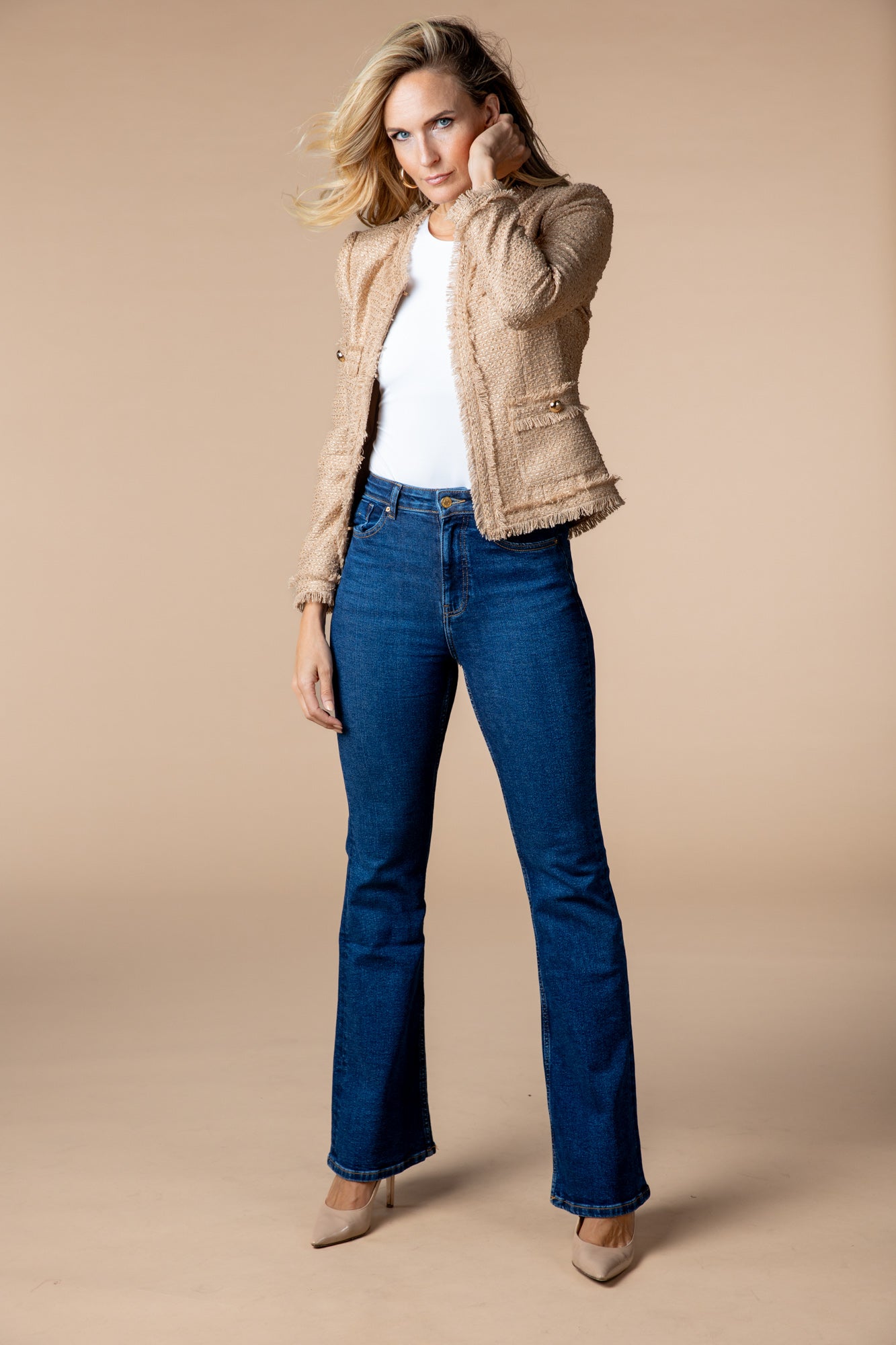 Jacke "Honey Glow" in Beige mit Goldschimmer getragen über Jeans für einen modernen und raffinierten Look. Die ausgefransten Enden der Jacke sorgen für einen trendigen Touch.